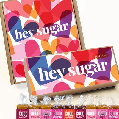 All-natural, gluten-free caramels shown with gift boxes full of colorful hearts and words that say "hey sugar." Each caramel is wrapped in positive quotes and Good Times; Good Heart; Good Life; Good Karma; and Good Vibes.