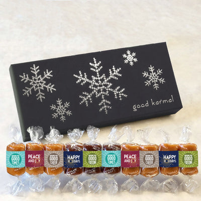 Gourmet caramels with colorful wrappers presented in a 10-piece holiday-themed gift box featuring metallic foil snowflakes. Caramel wrappers feature positive quotes and messages of good cheer, peace and joy, good fortune, good times. and happy holidays.