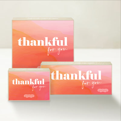 Three Good Karmal caramel gift boxes that say "thankful for you" on a serene and colorful background.