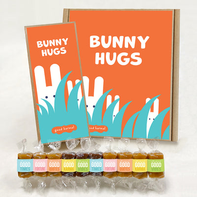Good Karmal caramel gift boxes that show white bunnies hiding in tall grass and the words "Bunny Hugs." Caramels shown are wrapped in positive words, Good Times; Good Fortune; Good Quotes; Good Karma; and Good Vibes. Sea salt, Chocolate Sea Salt and Vanilla caramels.