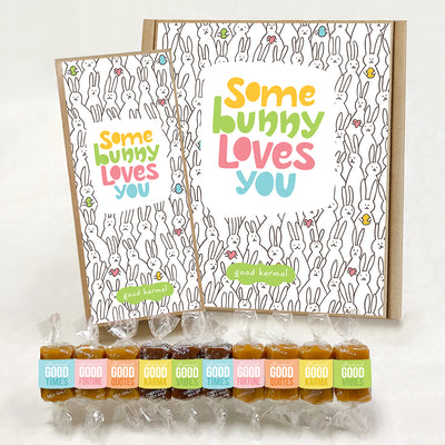 Good Karmal caramel gift boxes covered in illustrated black and white bunnies holding hearts and eggs and the colorful words "Some Bunny Loves You." Caramels shown are wrapped in a pastel Easter palette and the positive words, Good Times; Good Fortune; Good Quotes; Good Karma; and Good Vibes. Sea salt, Chocolate Sea Salt and Vanilla caramels.