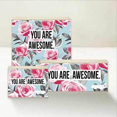 Three Good Karmal caramel gift boxes that say "You are awesome" on a background of roses.