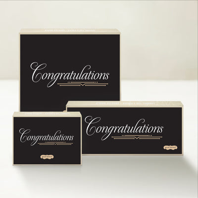 Three Good Karmal caramel gift boxes that say "congratulations" in an elegant script on a black background. 