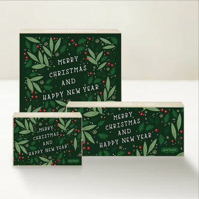 Three holiday-themed Good Karmal caramel gift boxes with messages of  Merry Christmas and Happy New Year with holly leaves. 