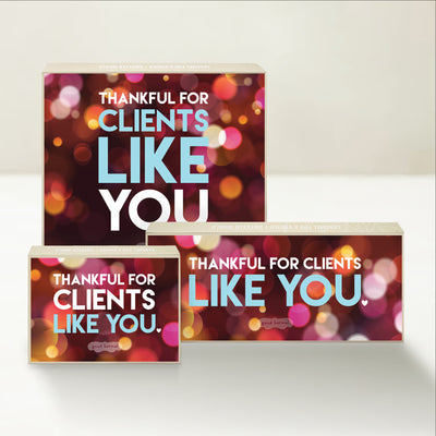 Three holiday-themed Good Karmal caramel gift boxes says "thankful for clients like you" on a festive, colorful background.