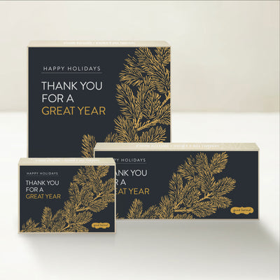 Three holiday-themed Good Karmal caramel gift boxes with illustrations of gold branches along with "happy holidays: thank you for a great year." 