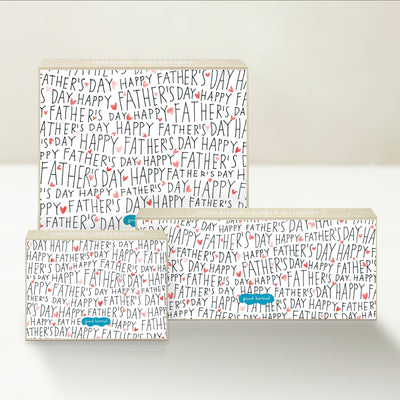 Three Good Karmal caramel gift boxes featuring handwritten "HAPPY FATHER'S DAY" repeated multiple times with pink and red hearts.
