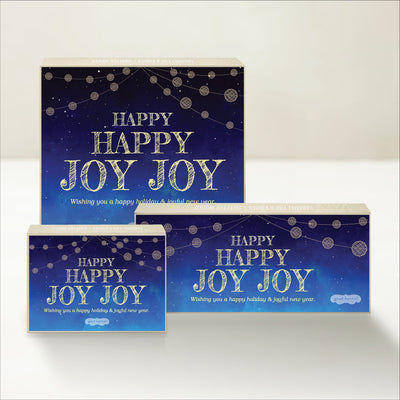 Three holiday-themed Good Karmal caramel gift boxes featuring string lights and "Happy Happy Joy Joy" festive holiday wishes.