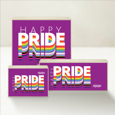 Three Good Karmal caramel gift boxes that say "Happy Pride" on a vibrant, colorful background.