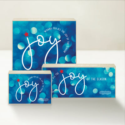 Three holiday-themed Good Karmal caramel gift boxes featuring a festive, bubbly background and wishing all the joy of the season.