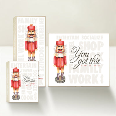 Three holiday-themed Good Karmal caramel gift boxes featuring an overwhelmed nutcracker saying "you got this" and wishing happy holidays.