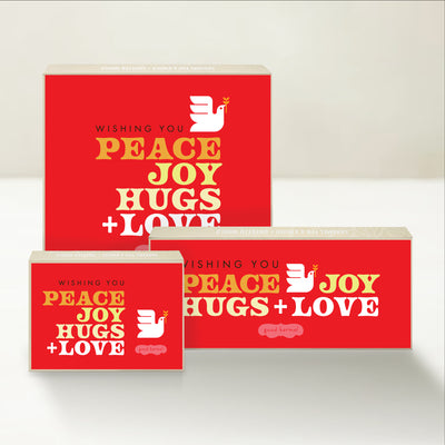 Three holiday-themed Good Karmal caramel gift boxes with messages of Peace, Joy, Hugs, and Love with a retro-inspired design.