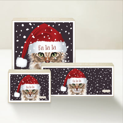 Three holiday-themed Good Karmal caramel gift boxes with a cat wearing a santa hat embroidered with "fa-la-la" on its brim.