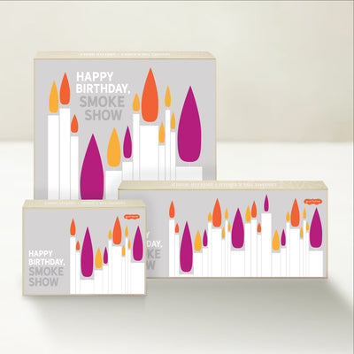 Three Good Karmal caramel gift boxes that say "Happy Birthday Smoke Show" surrounded by colorful birthday candlelight