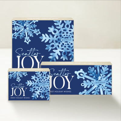 Three holiday-themed Good Karmal caramel gift boxes featuring snowflakes, sweet holiday wishes, and "scatter joy."