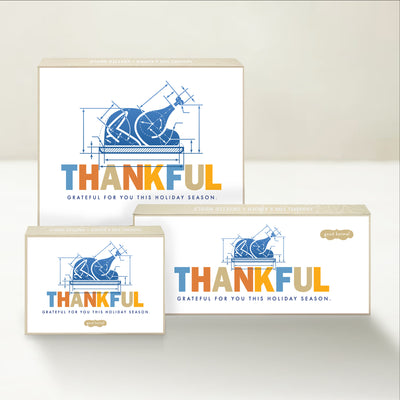 Three holiday-themed Good Karmal caramel gift boxes with a blueprint-inspired Thanksgiving illustration sharing a message of gratefulness. 