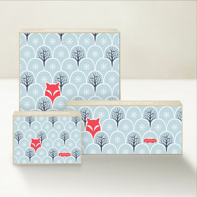 Three holiday-themed Good Karmal caramel gift boxes featuring a whimsical fox illustration in a winter landscape. 