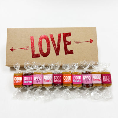 Gourmet caramels with colorful wrappers presented in a 10-piece gift box with foil-embossed arrows and the word Love. Caramel wrappers feature positive quotes and motifs of good vibes, good times, good karma, good life, and good heart.