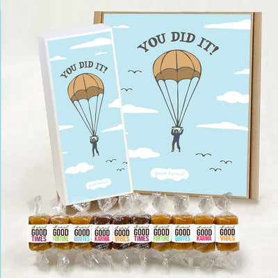 All-natural caramel wrapped in positive quotes in a gift box that has an illustration of a person parachuting and the words YOU DID IT!